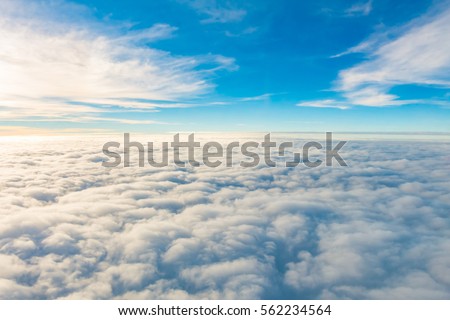 Sunrise above clouds from airplane window Royalty-Free Stock Photo #562234564