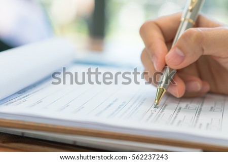 Hand with pen over application form Royalty-Free Stock Photo #562237243