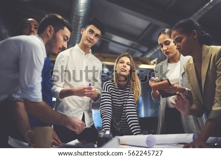 Young male and female students practicing in blueprints creation during university training lesson in office working in team with skilled leader controlling process and sharing ideas about project  Royalty-Free Stock Photo #562245727