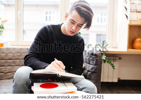 Picture of serious caucasian student in library learning education material with books. Look at book.
