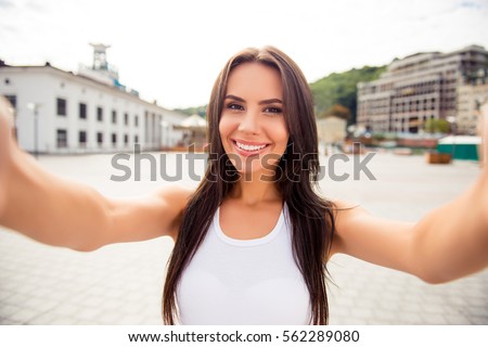 Young smiling girl making selfie on the background of the city