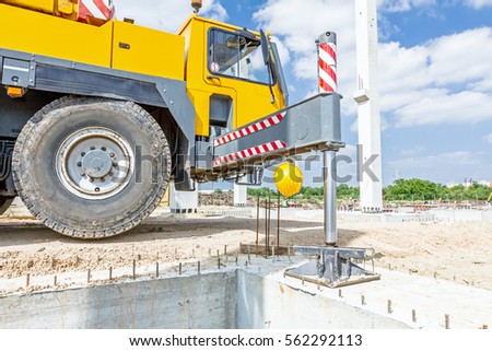 Extended side hydraulic outrigger to increase crane stability until is under heavy duty.  Royalty-Free Stock Photo #562292113