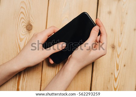 is holding a phone in his hand a wooden background