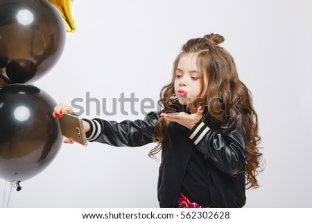 Little modern hipster girl in fashion clothes and baloons, Selfie, kiss. Take photo on telephone