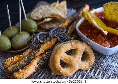 Party mix (tortilla chips, pile of bread sticks, pretzels and olives) 