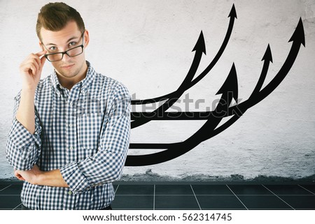 Handsome young businessman with chart arrows on wall. Financial growth concept