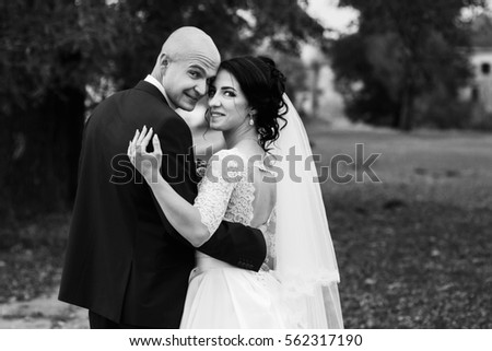 Black and white picture of newlyweds looking over their shoulders in park
