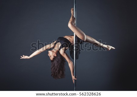 Young slim pole dance girl of asian appearance on a black studio background Royalty-Free Stock Photo #562328626