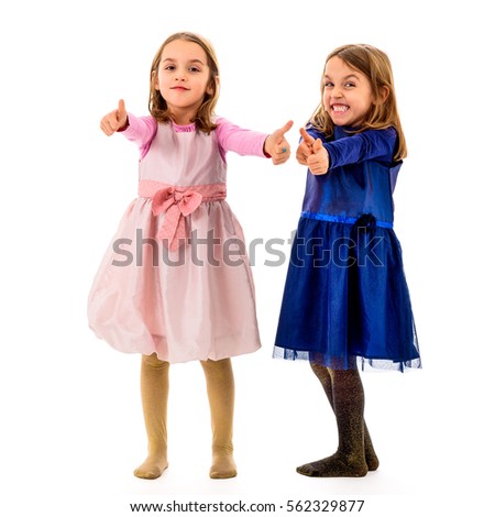 Identical twins children posing in studio, fooling around making different facial expressions, making thumbs up gesture. Concept of encouragement, acceptance and being right.