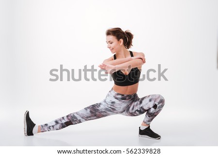 Picture of happy young fitness lady standing isolated over white background and stretching her body