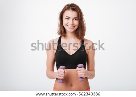 Picture of smiling young fitness lady standing isolated over white background while make exercises with dumbbells