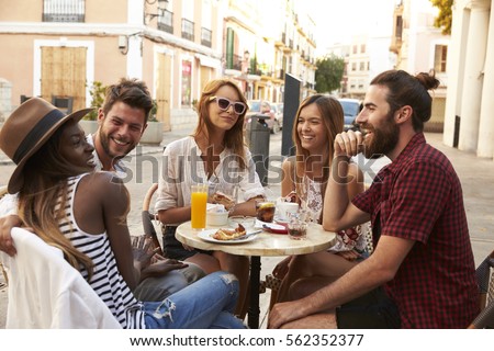 Friends on vacation laughing outside a cafe in Ibiza Royalty-Free Stock Photo #562352377