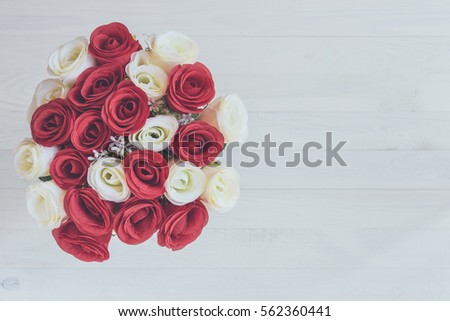 Bouquet of artificial rose flower on wooden plank background. Top view