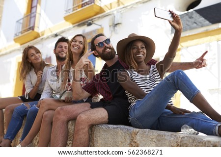 Five friends sitting on a wall in Ibiza taking a selfie Royalty-Free Stock Photo #562368271