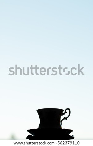 Silhouette of a vintage teacup against blue sky background