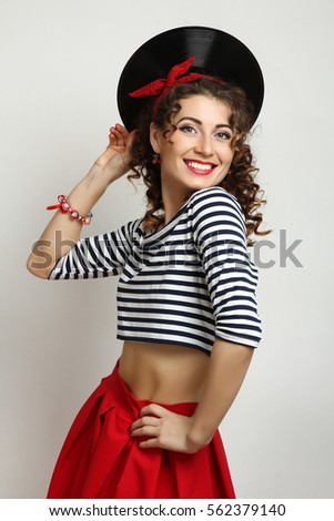 Girl pin-up posing with a music plate in studio.