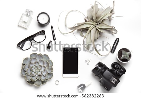 Stylized photo. Minimal flatlay with smartphone, candle, camera,perfume, nail polish, cactus, glasses and succulent plants on white background. Feminine workspace desktop top view. Mock up