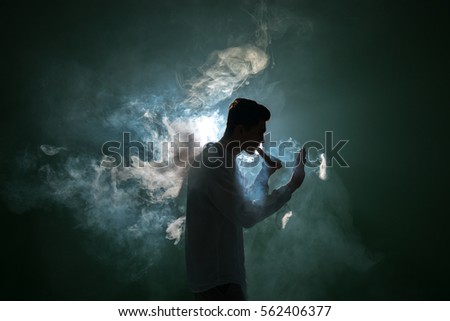 The man smoke an electronic cigarette with a ring on the dark background