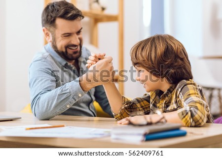 Positive delighted male relatives competing arm wrestling