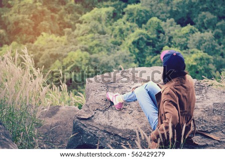The girl sitting on the rock mountain , relaxing on the top of the mountain.