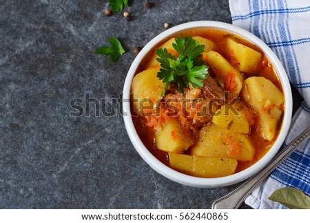 Homemade stew with meat and vegetables on a black background