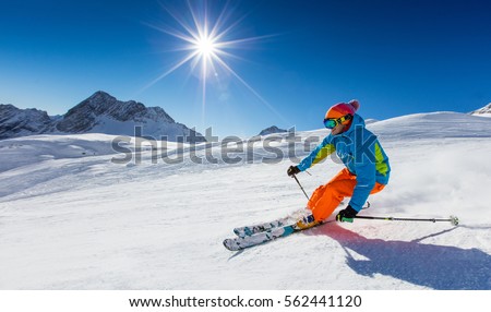 Skier skiing downhill during sunny day in high mountains Royalty-Free Stock Photo #562441120