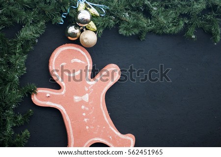 Cardboard Christmas man on a wooden blackboard decorated pine tree branches with toys. free space for greeting text.