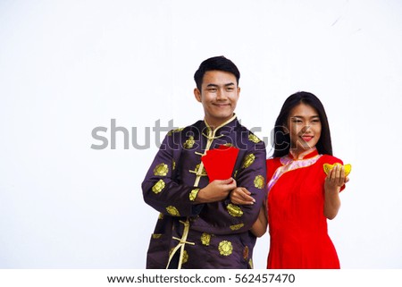 A smiling Chinese man is holding red packet or Ang Pao gift for Chinese New Year with Chinese woman hold golden ingot in hand. 
