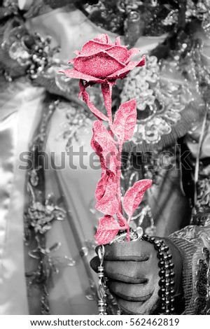 Venetian mask holding a rose during a Carnival. Venice (Italy). Toned photo.