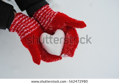 woman in red mittens holding a snowy heart