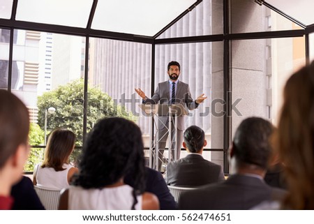 Hispanic man gesturing to audience at business seminar