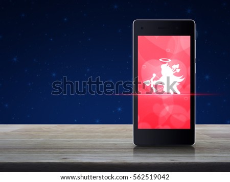 Cupid icon on modern smart phone screen on wooden table over fantasy night sky and moon, Internet online love connection, Valentines day concept