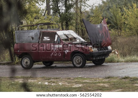 on the road, an old broken car with open hood Royalty-Free Stock Photo #562554202