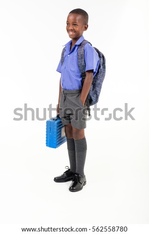 African boy wearing his school uniform and holding a school bag ready to go back to school.