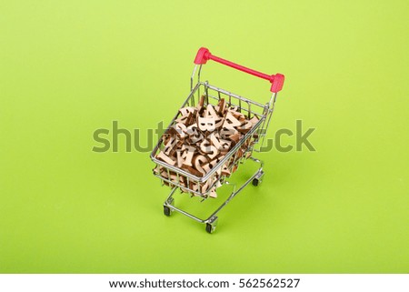 Shopping basket with letters of the alphabet made of wood on a green background