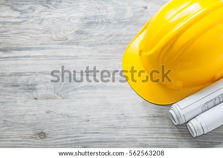 Hard hat construction plans on wooden board building concept. Royalty-Free Stock Photo #562563208
