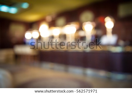 Blur abstract background interior of dark brown bar. Empty glasses for wine above a bar rack. Classic bar counter with bottles in blurred background. Interior of pub or bar at night. Luxury restaurant