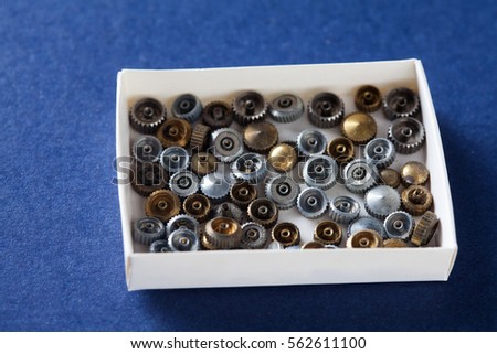 Vintage clockwork parts in paper box. Blue background, macro shallow depth of field photo.