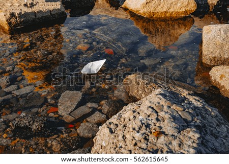 paper boat on the water between rocks. paper ship sailing