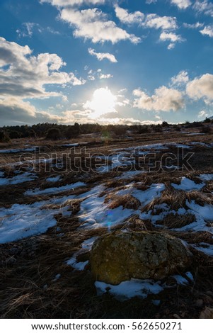 Beautiful blue cloudy sky winter landscape with stone. Sunset.