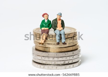 Retired / elderly couple sitting on euro coins Royalty-Free Stock Photo #562669885