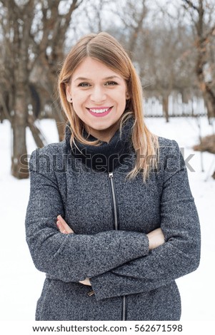 Picture of a smiling woman with the arms crossed outdoor