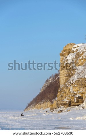 Frozen beauty of winter landscape. Stone hill on the bank of the frozen river. 