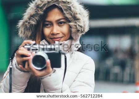 Young and cute girl in winter coat, photographing outside in the cold open air