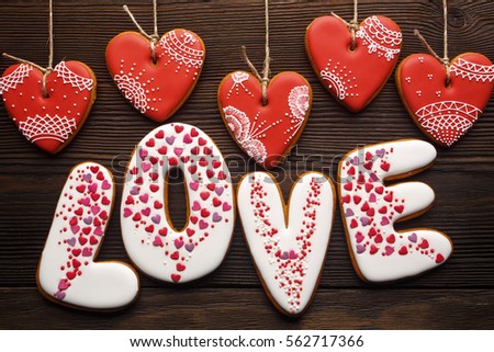 Close up of festive decoration for Valentines day on wooden background. Sweet cookies of gingerbreads hearts, word 'Love'.
