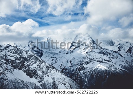 Dramatic panorama of snowy high mountains below cloudy sky in winter time Wild nature picture