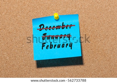 February beginning concept. Inscription with strikeout December and January month, written on sticker pinned at board