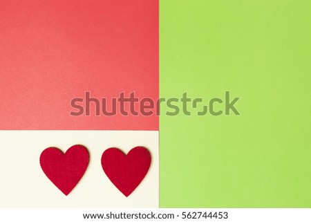 Two hearts on greenery, red and yellow colored paper background. Top view. Copy space for text