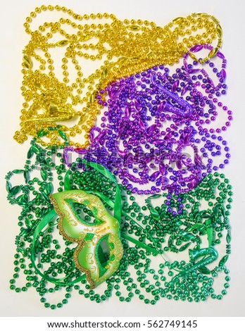 Mardi Gras beads in green, gold and purple and green venetian mask 