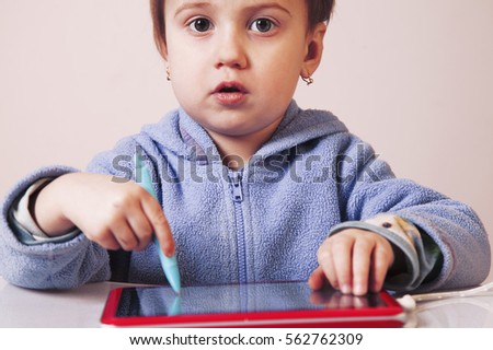 Baby girl drawing on the  graphics tablet. The young art and web designer. (Humorous picture)